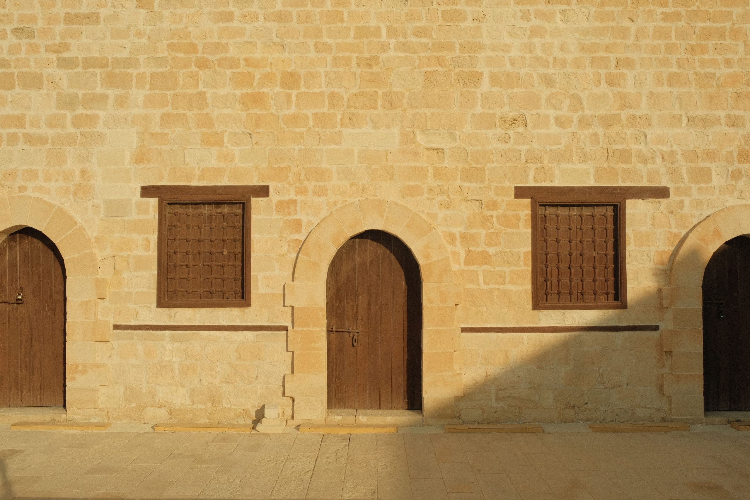 Arched wooden doors set into a golden sandstone facade